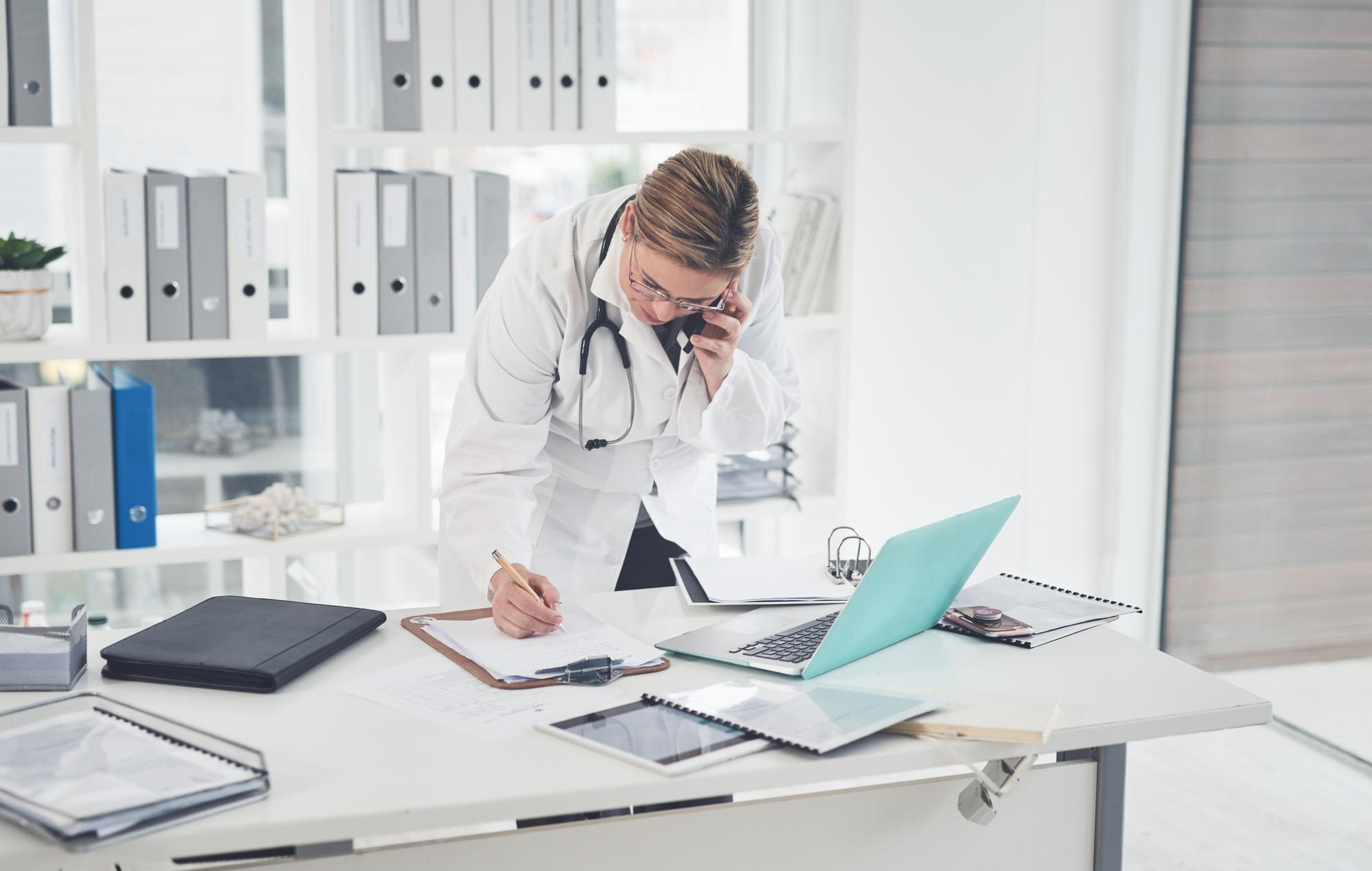 Physician reviewing paperwork in a clinic, symbolizing time-management and reduced burnout in a medical practice